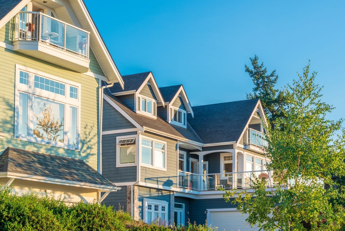 A perfect neighborhood. Houses in suburb at Summer in the north America. Top of a luxury house with nice window over blue and white sky.